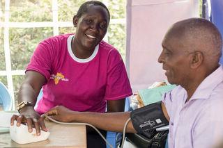 A community volunteer taking a person’s blood pressure reading